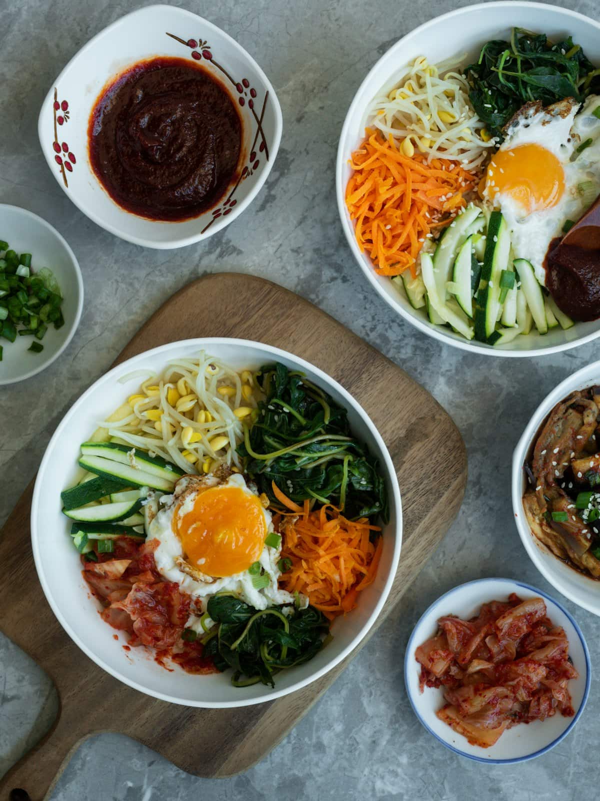 A bibimbap bowl arranged with fried egg, carrots, cucumber, spinach, and kimchi
