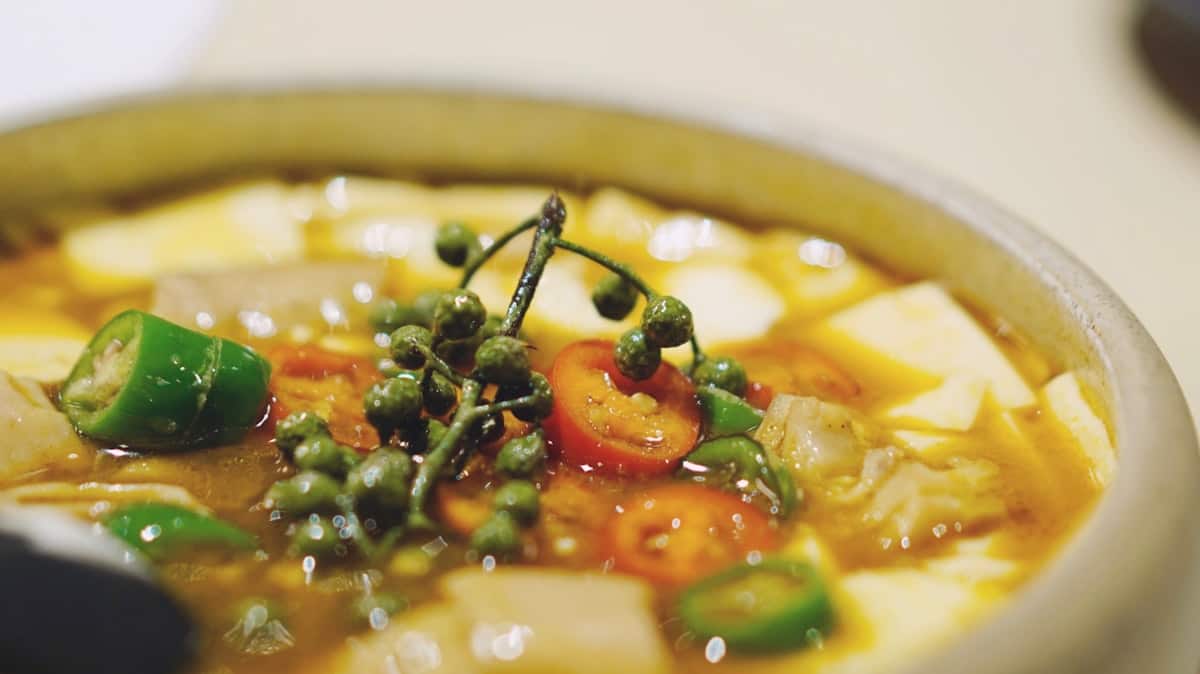 A bubbling Korean soybean stew with tofu and chili in a stone pot