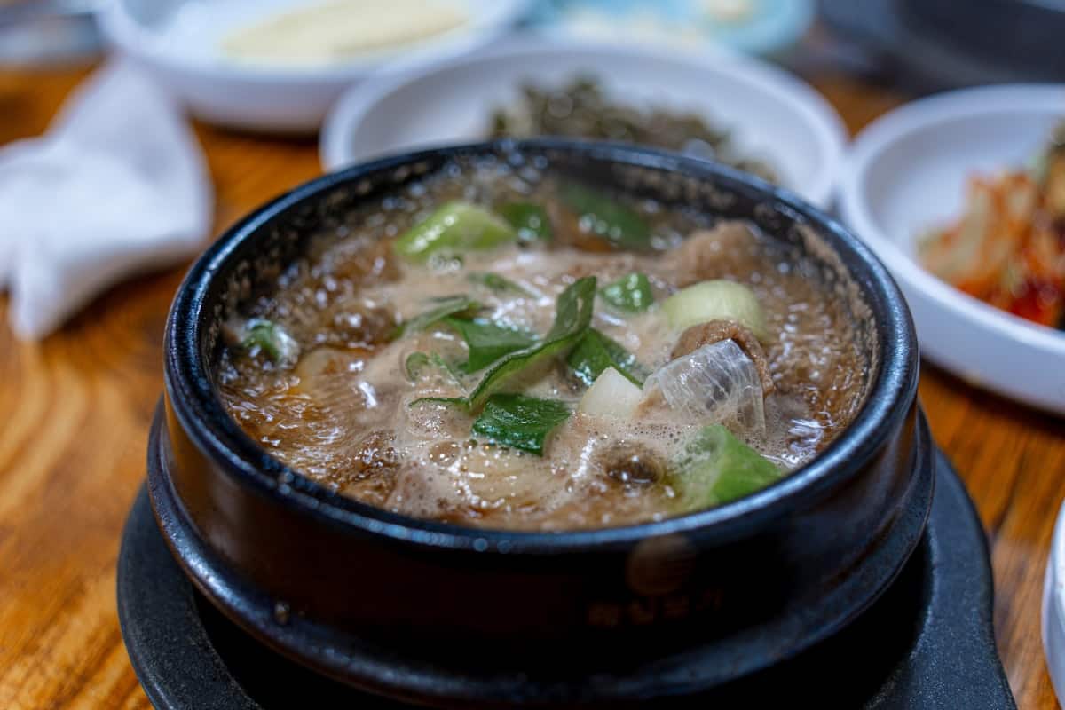 Doenjang jjigae bubbling in a stone pot with tofu and vegetables