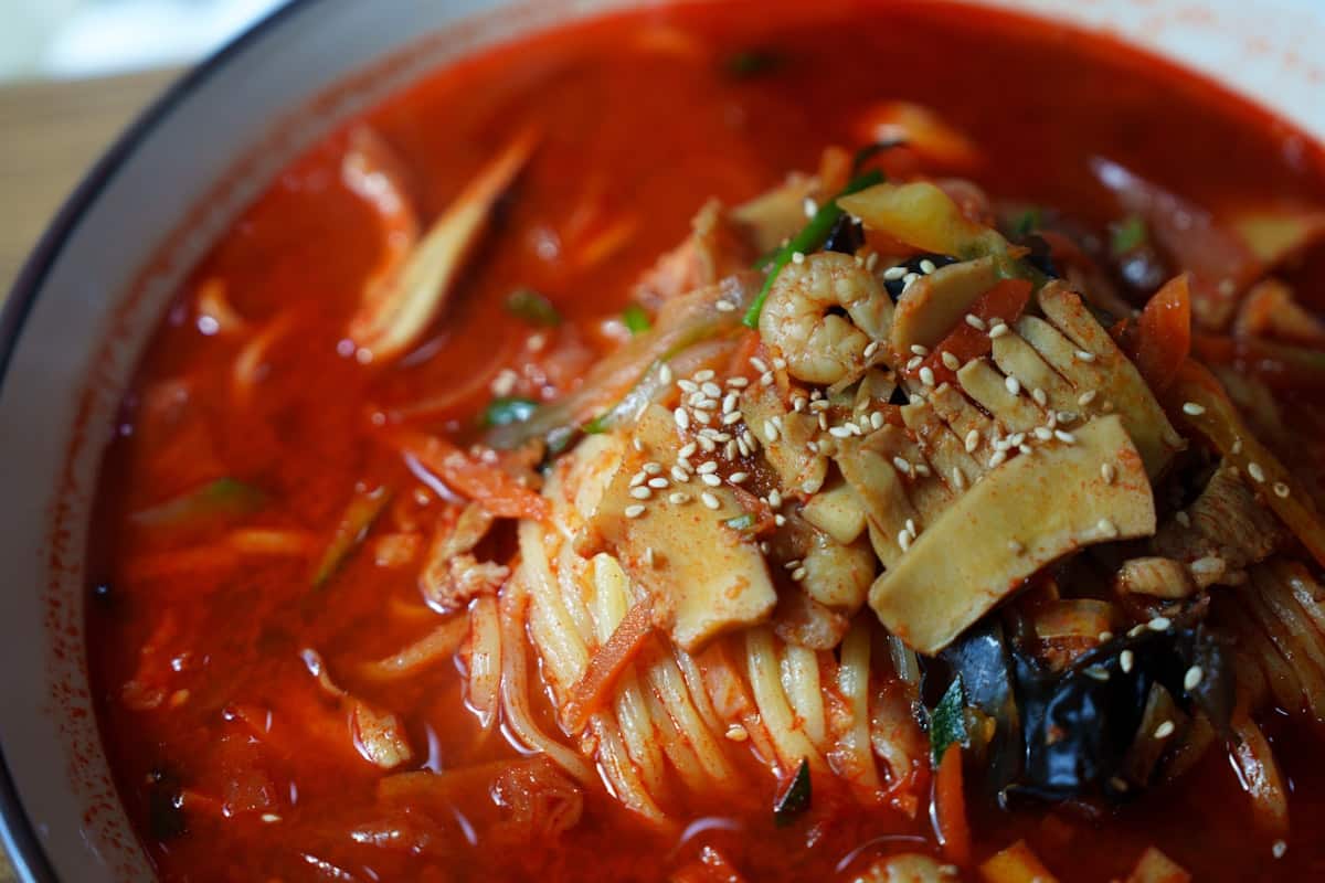 Spicy red seafood noodle soup with shrimp and vegetables in a bowl