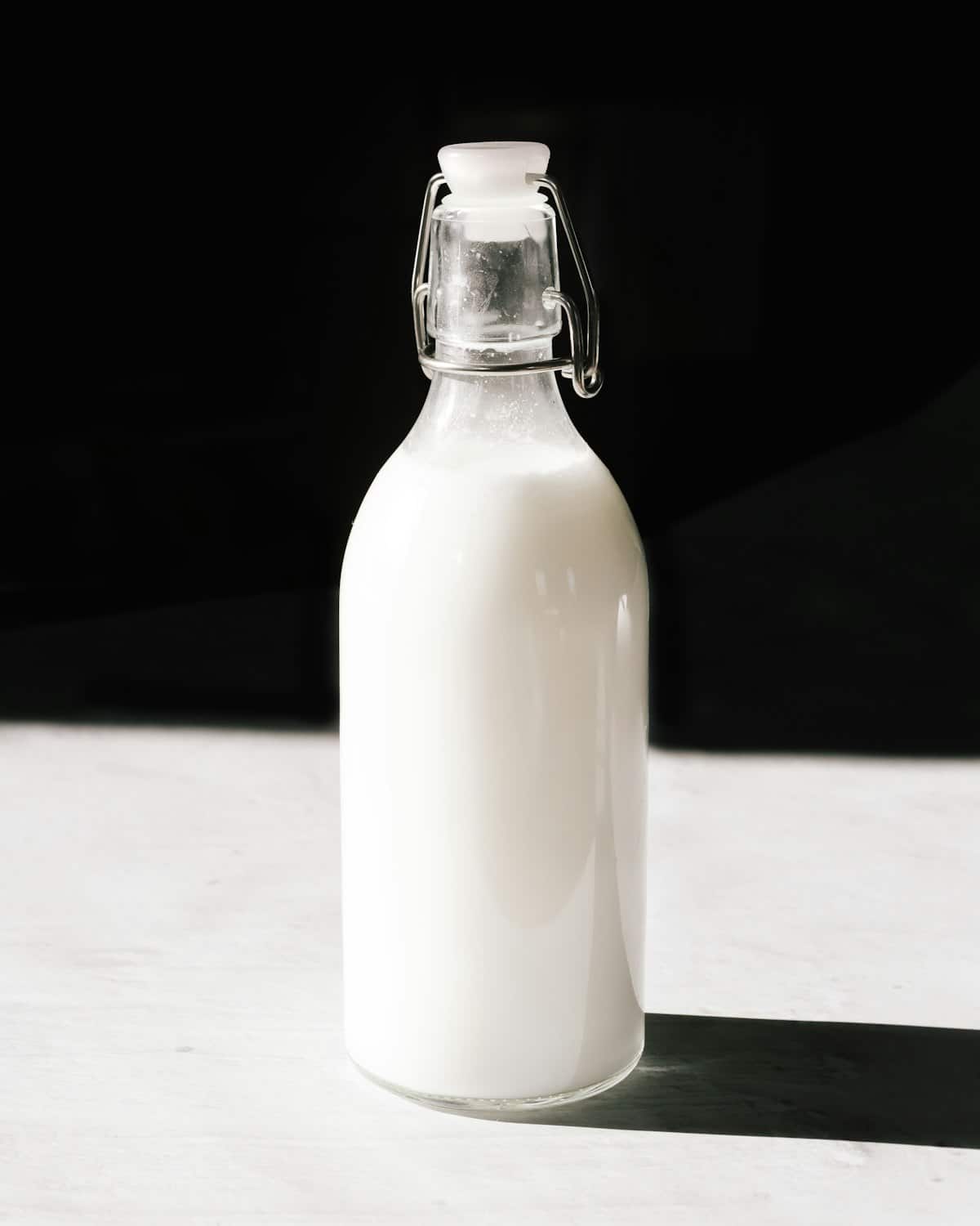 A swing-top glass bottle filled with cloudy white liquid