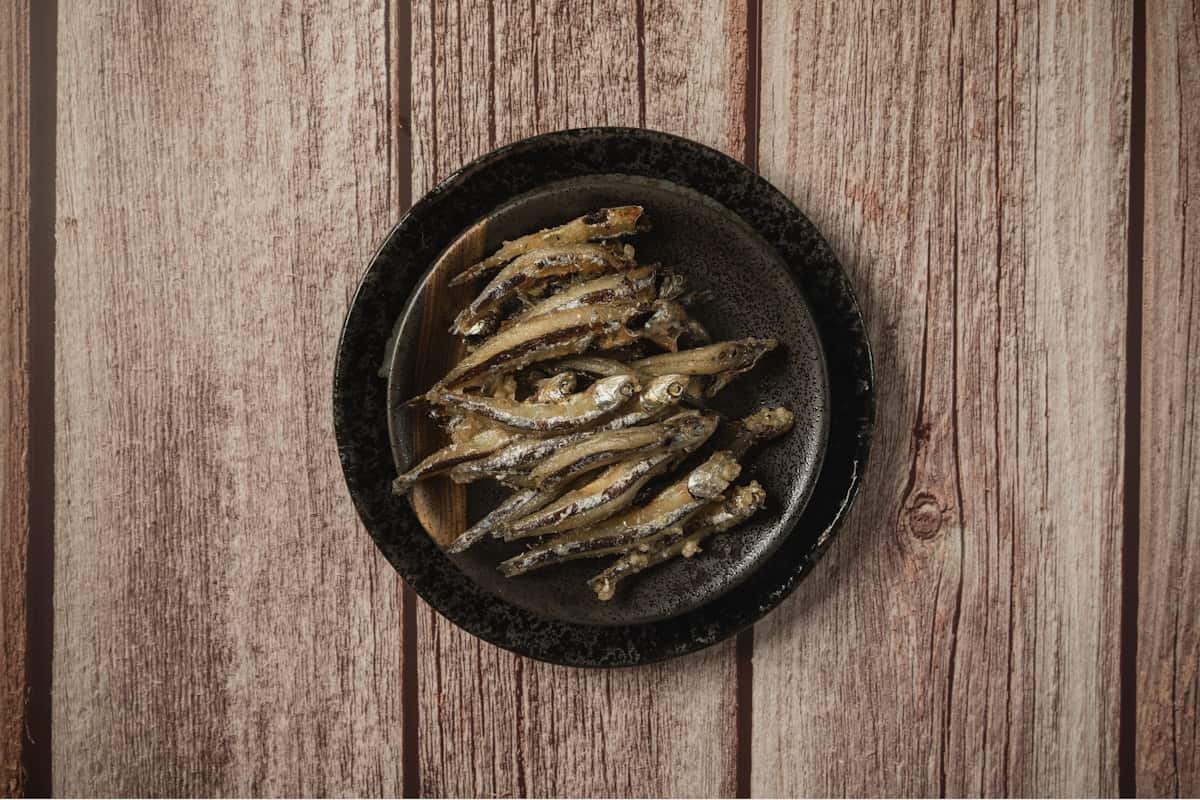 Small dried anchovies on a dark plate
