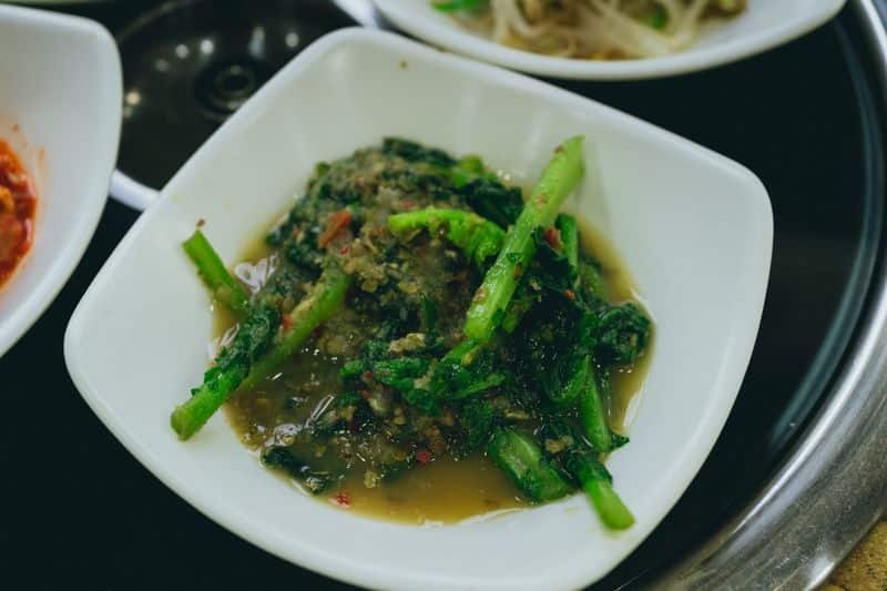 Seasoned dark leafy greens with visible chili flecks in a bowl