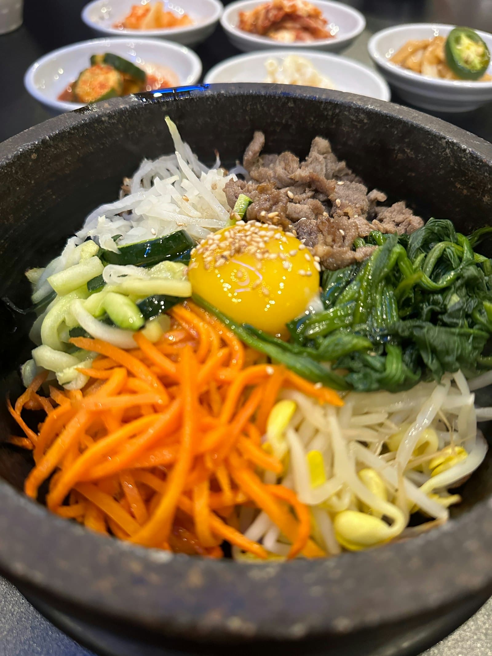 Dolsot bibimbap in a stone bowl topped with a raw egg yolk and vegetables