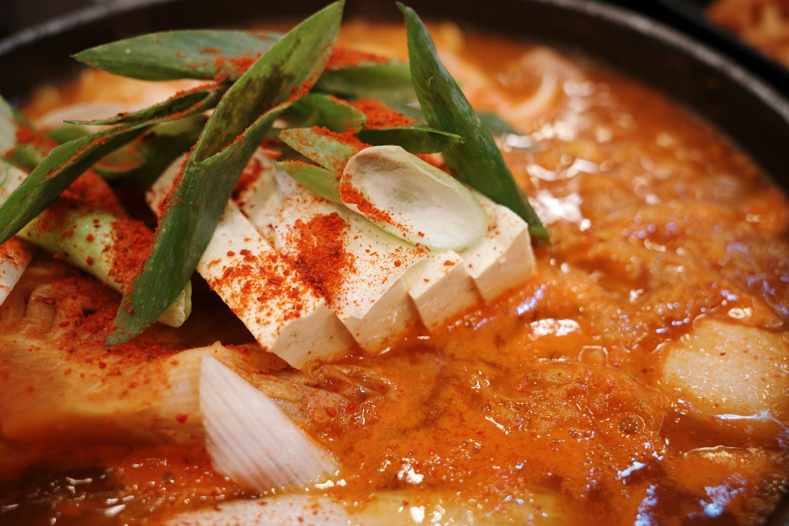 Close-up of a spicy Korean stew with tofu and scallions