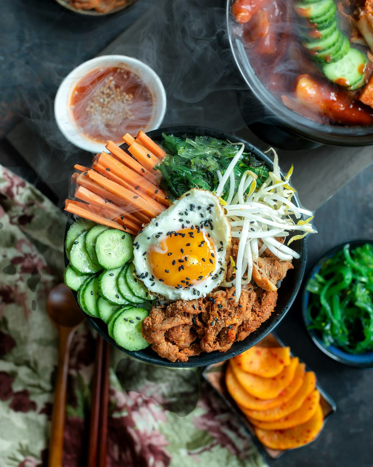A bibimbap bowl with steam rising, arranged by color into distinct sections