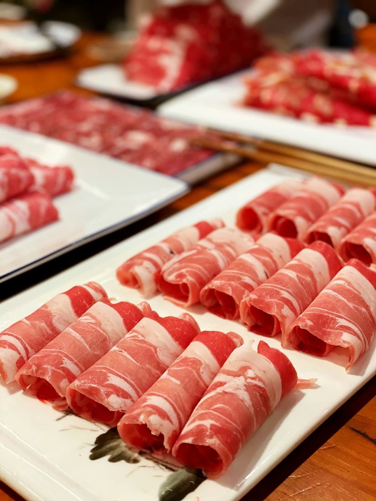 Thin rolled slices of raw marinated beef arranged on a platter