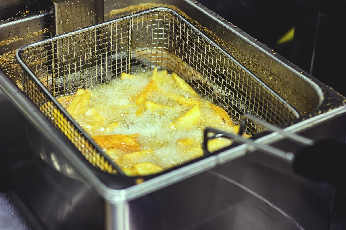 A fryer basket of golden fried food bubbling in oil