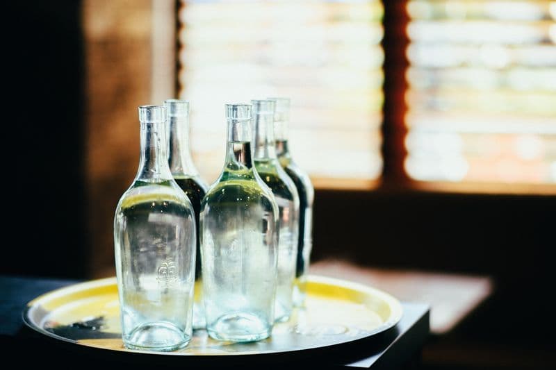 Clear glass bottles on a tray in a dim bar setting