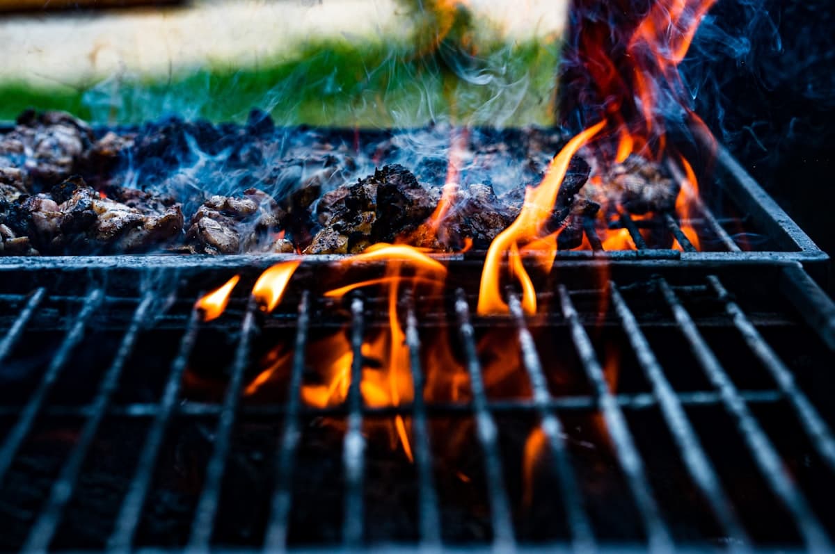 Flames and smoke rising through a charcoal grill grate