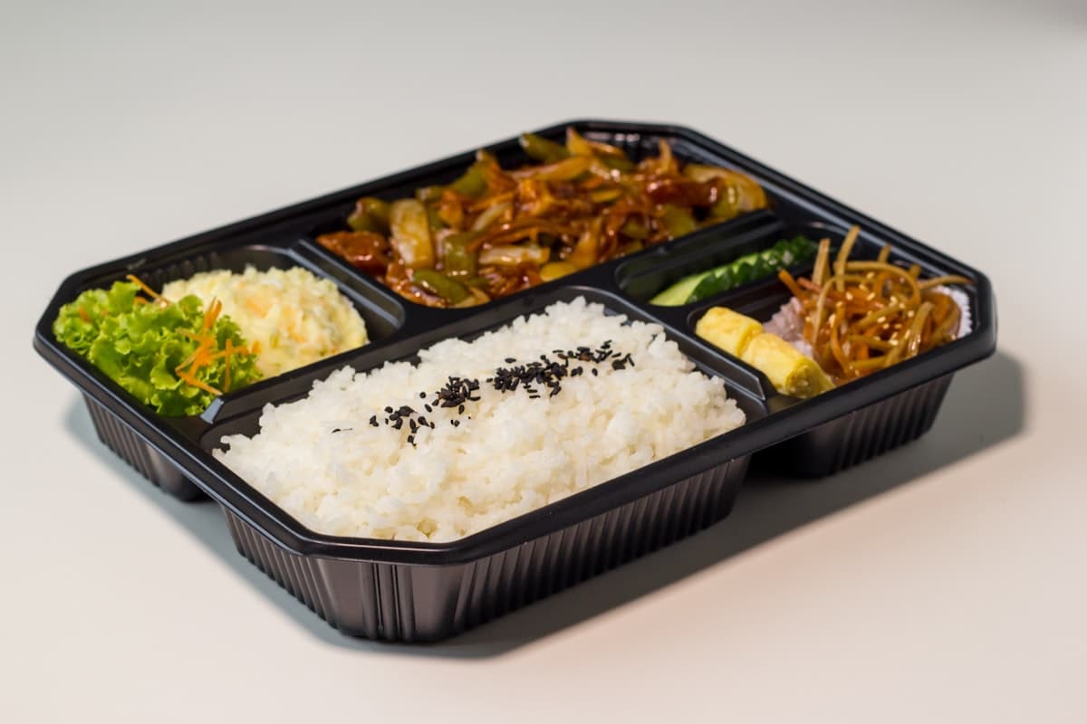 A Korean lunchbox (dosirak) with rice, vegetables, and a rolled egg omelette