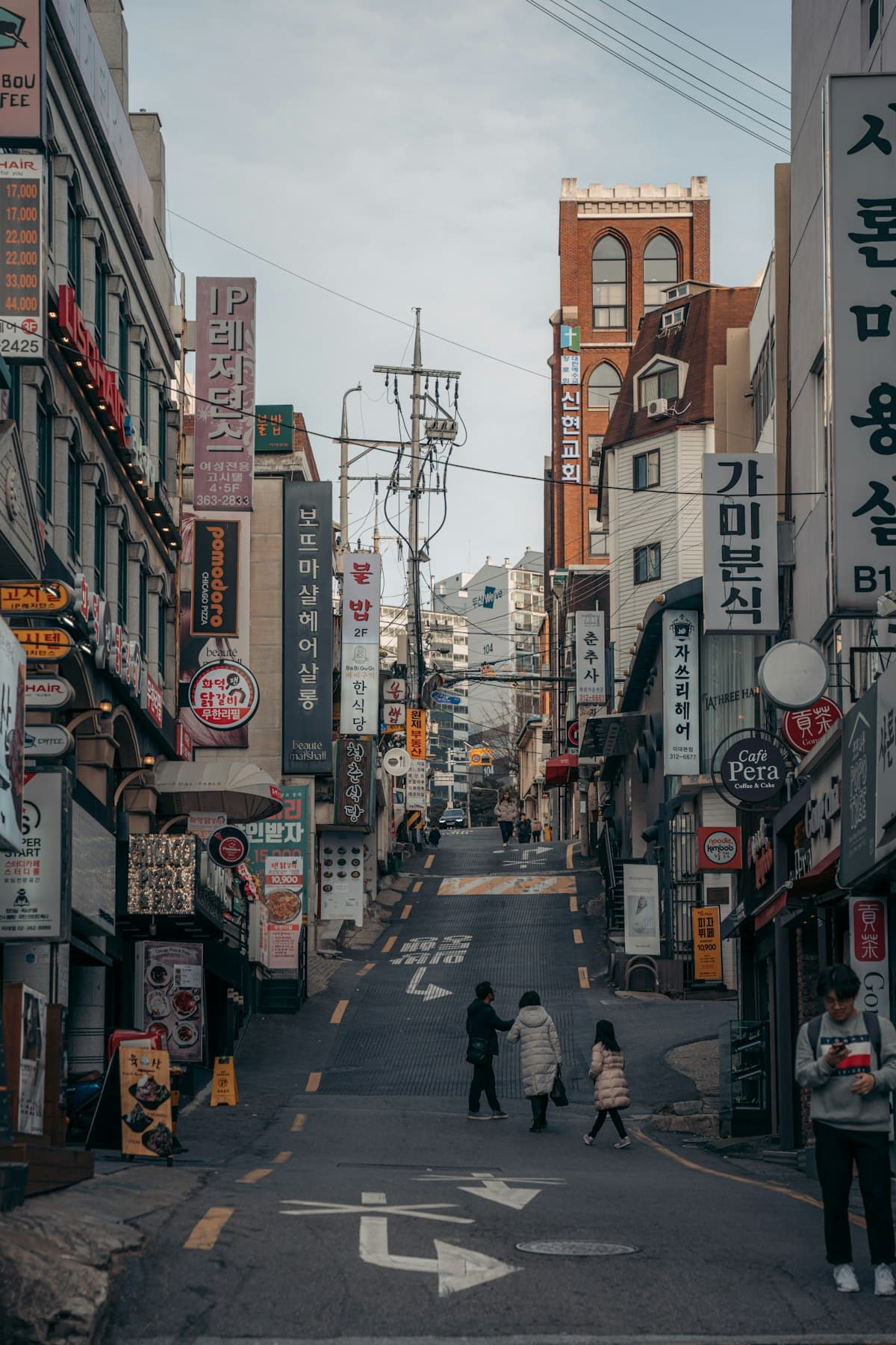 A narrow Seoul shopping street lined with signs and pedestrians