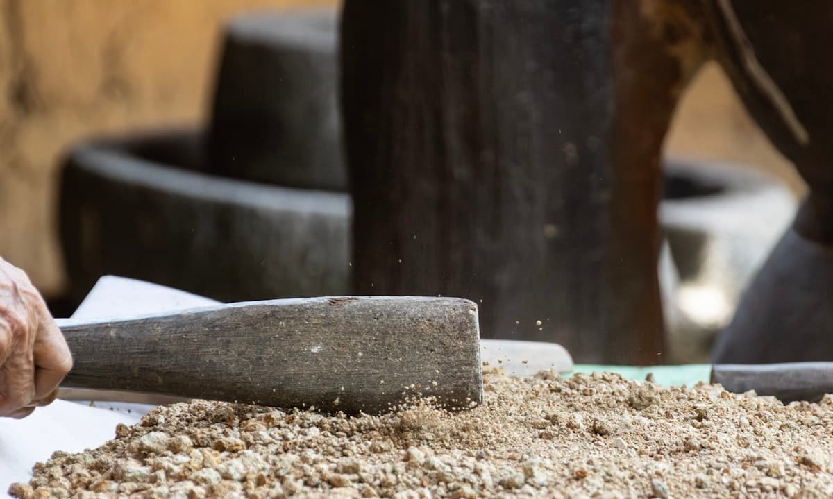 A large wooden mallet pounding grain by hand