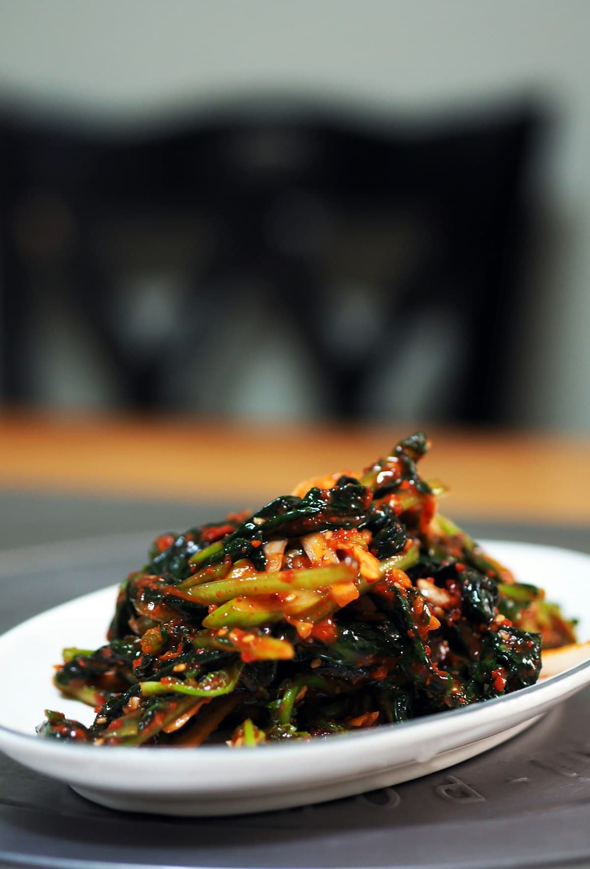 A leafy green vegetable kimchi variety plated on a white dish
