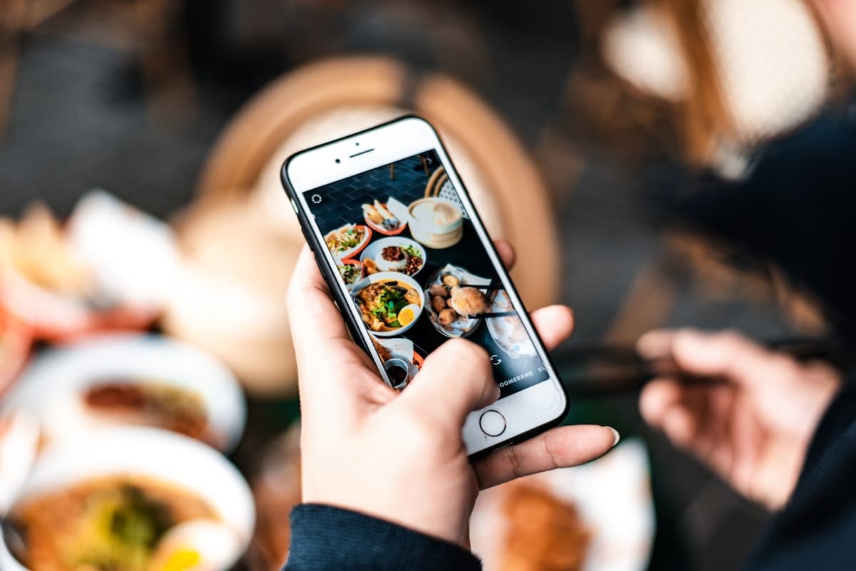A hand holding a phone photographing a spread of food