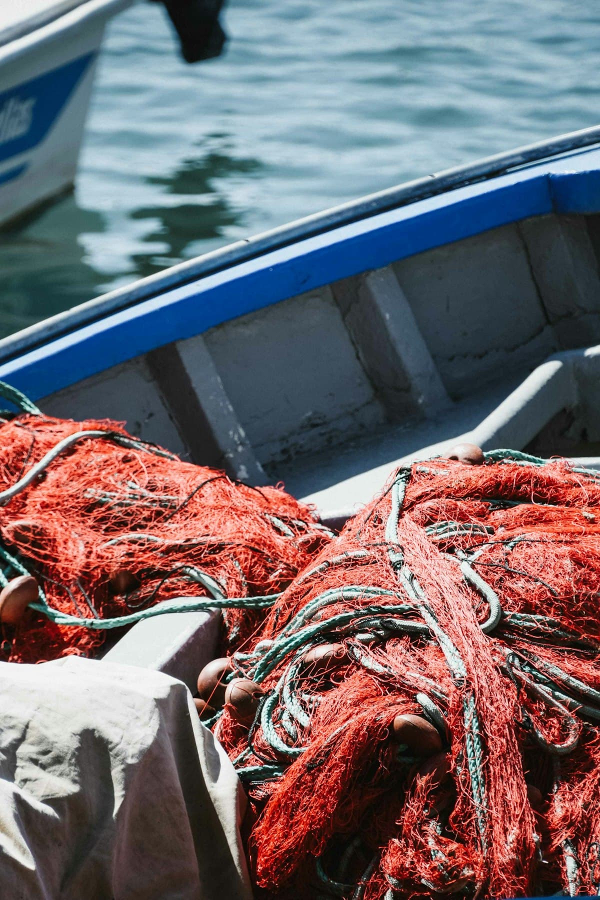 A tangle of red fishing net on a boat by the water