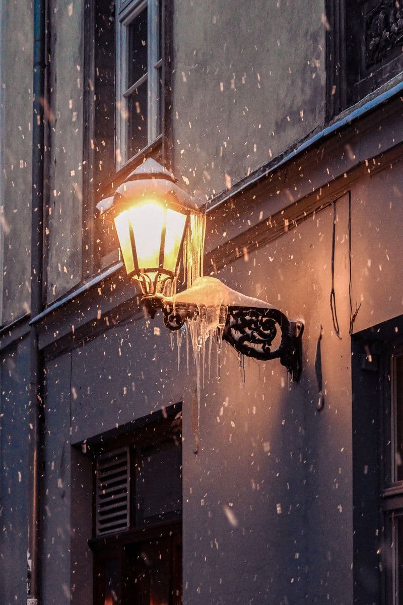 A glowing street lantern during a snowy night