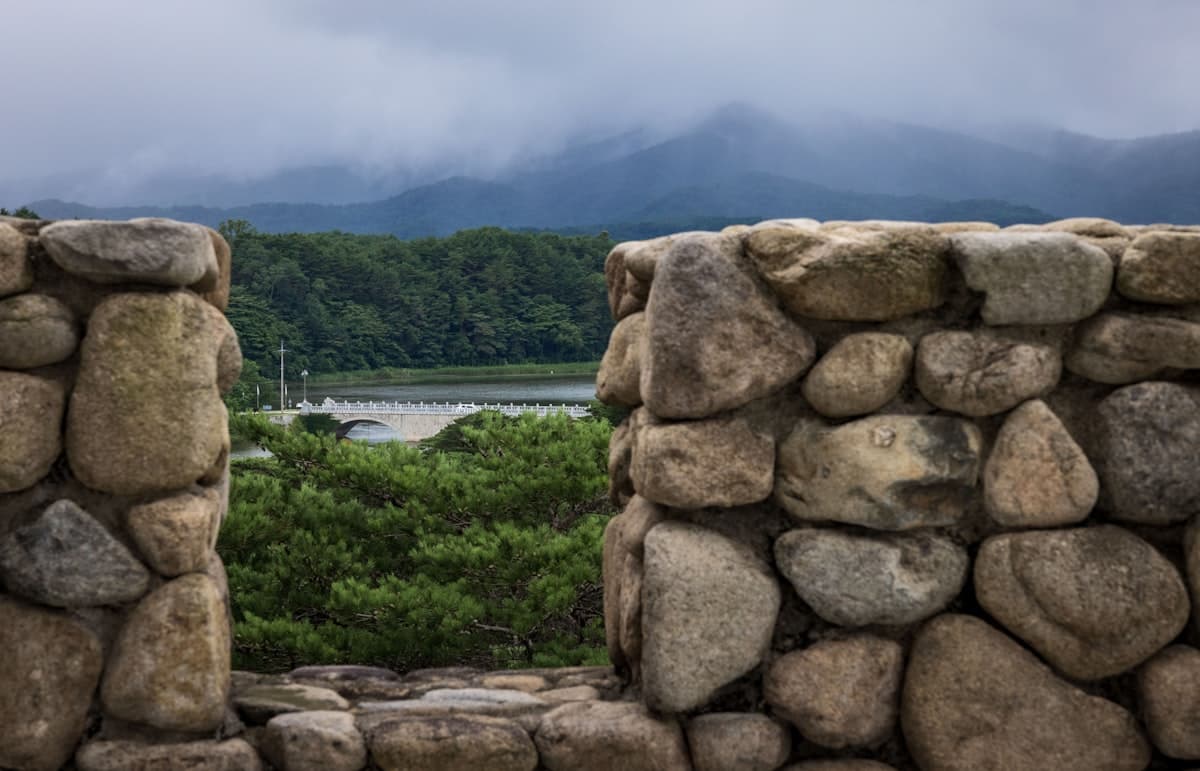 An ancient stone fortress wall overlooking misty mountains