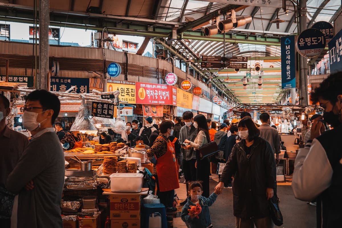 A crowded traditional Korean market with food stalls and shoppers