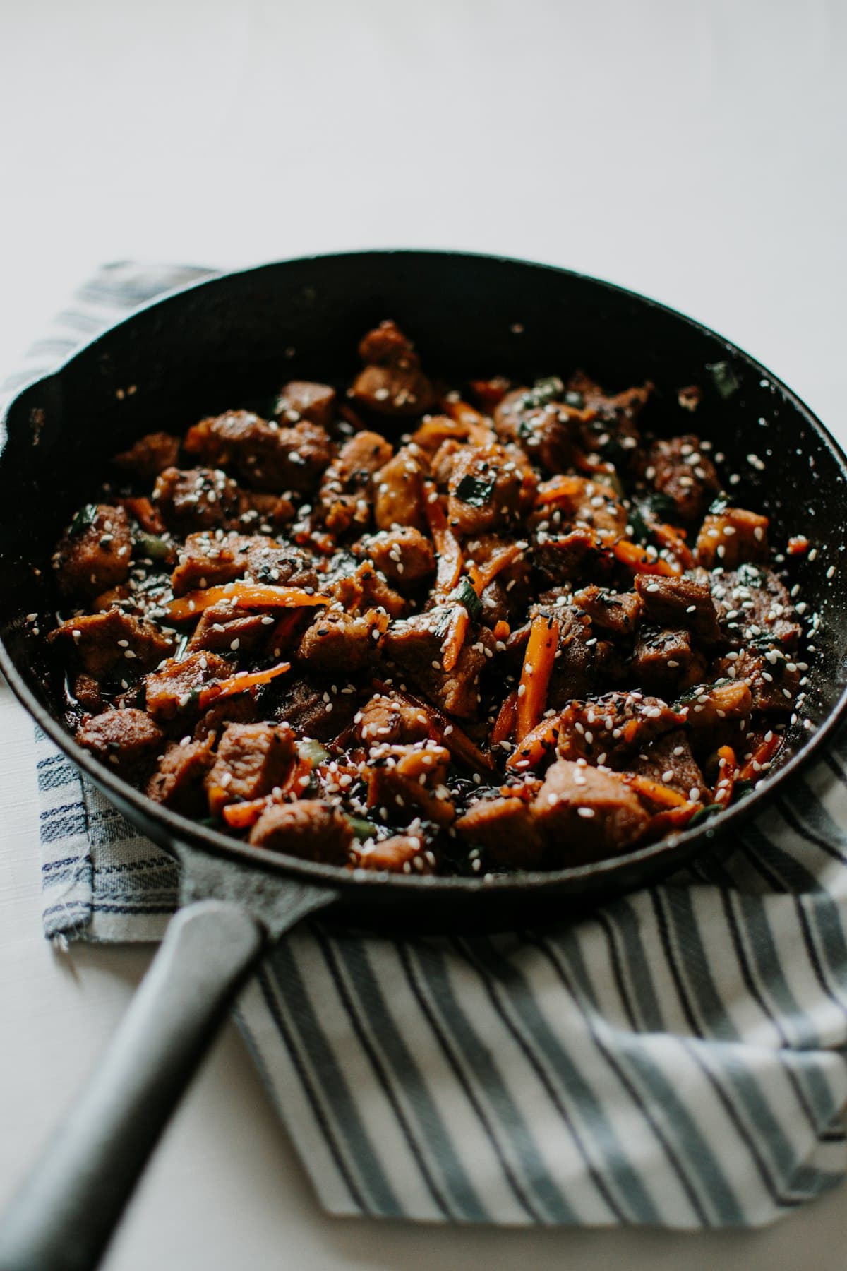 Soy-glazed diced meat and carrots with sesame seeds in a pan