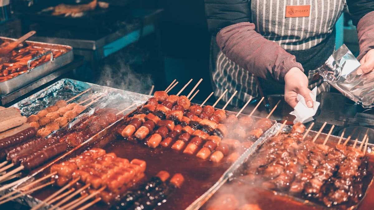 Skewered street food glazed in sauce at a steaming market stall