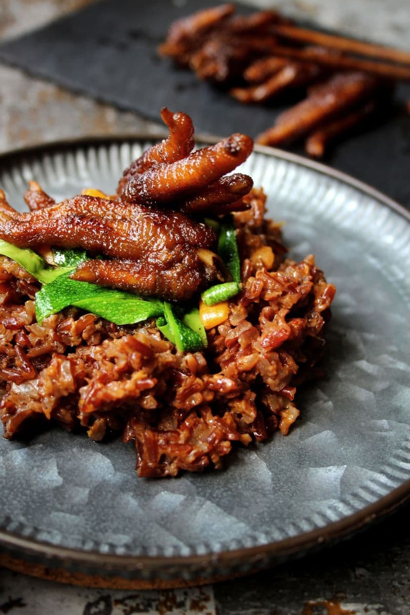 Glossy dark red glazed chicken feet served over rice with vegetables