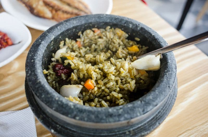 Seasoned rice with carrot, jujube, and ginkgo nuts served in a hot stone pot