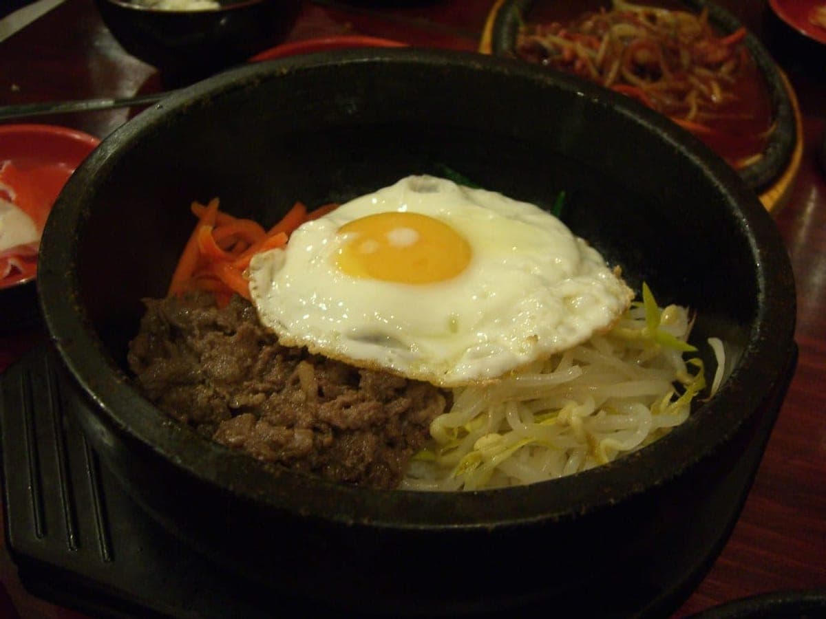 Stone pot bibimbap with vegetables, beef and a fried egg on top