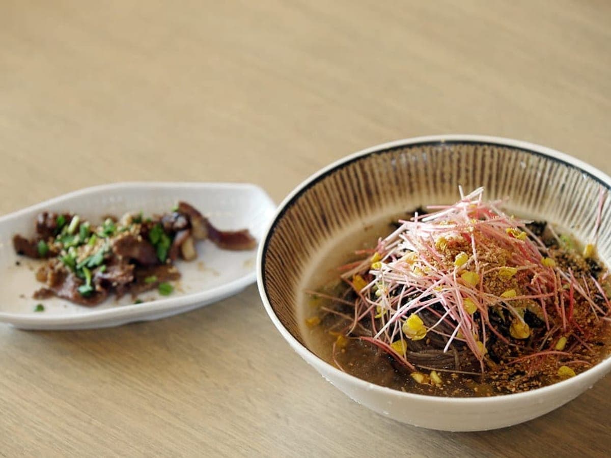 Buckwheat noodles topped with vegetables and sesame in a wide bowl