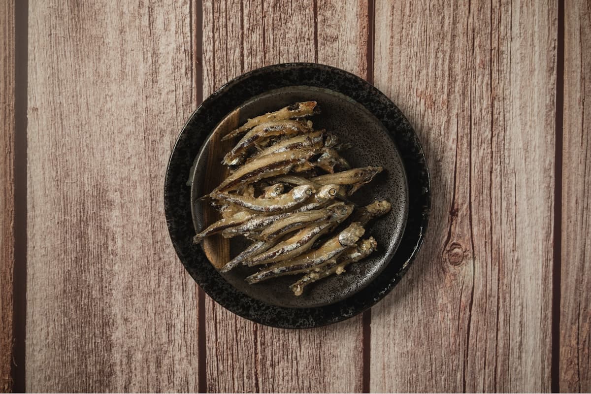 Small dried anchovies on a dark plate