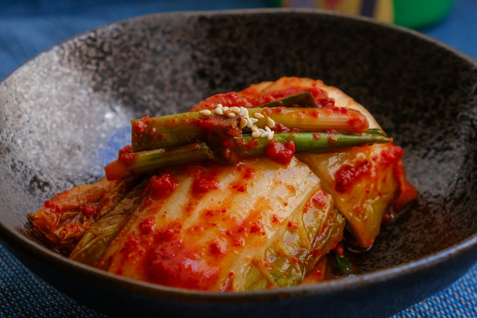 A whole napa cabbage kimchi leaf coated in red chili paste in a rustic bowl