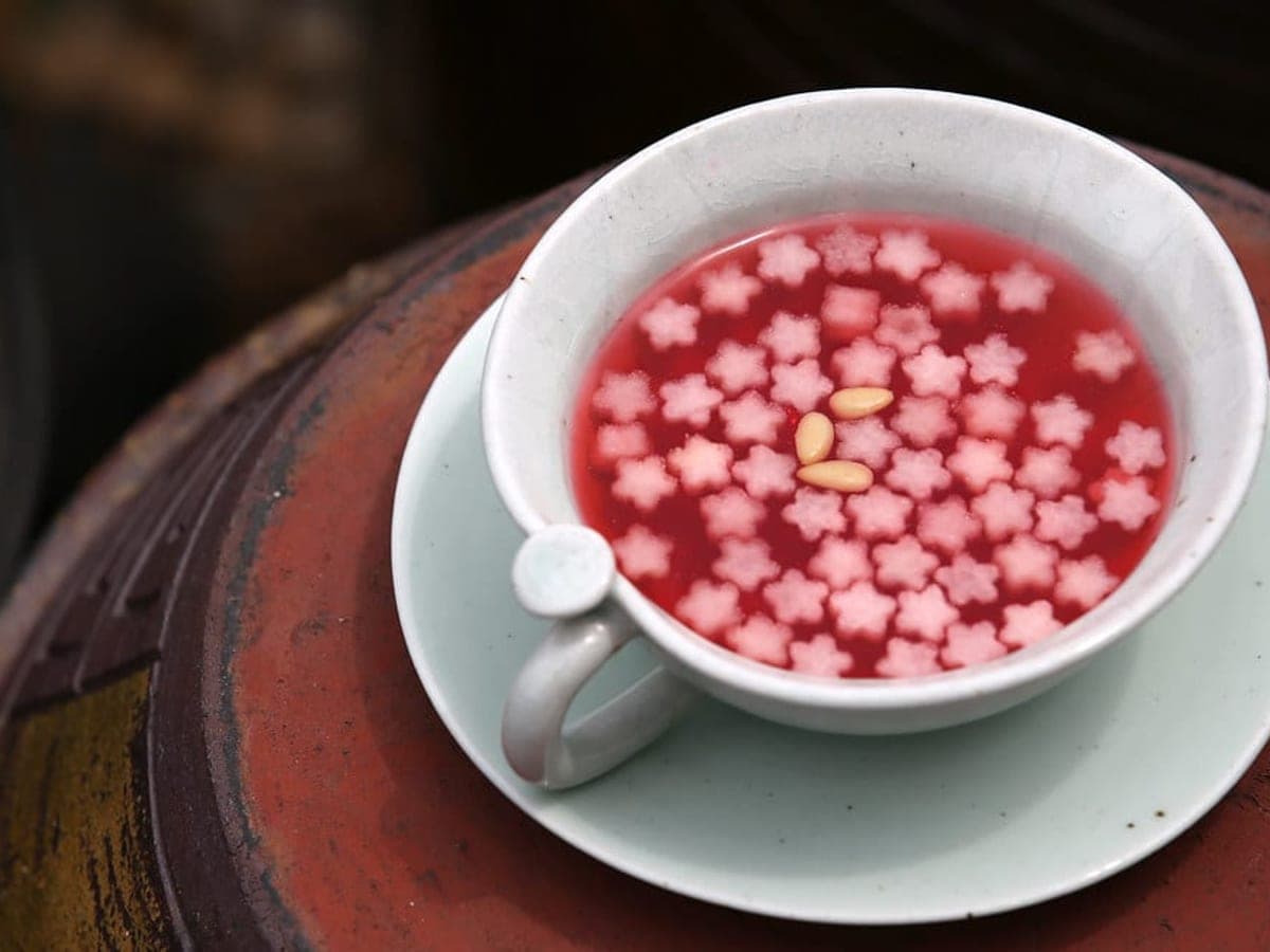 Deep pink berry punch in a white bowl with flower-shaped fruit garnish floating on top