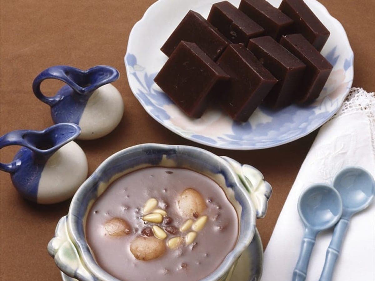 Thick dark red bean porridge in a bowl with small white rice balls
