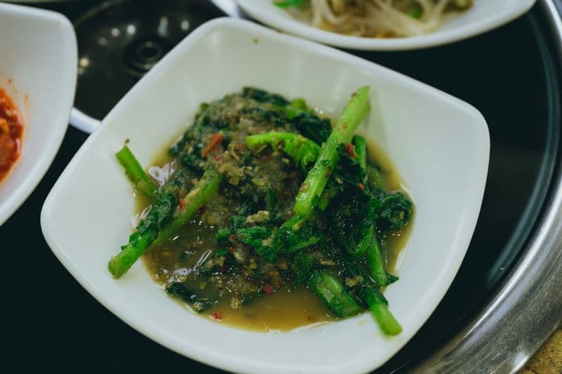 Seasoned dark leafy greens with visible chili flecks in a bowl