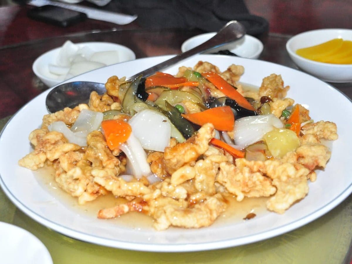 Battered fried pork pieces with vegetables in a glossy sweet and sour sauce