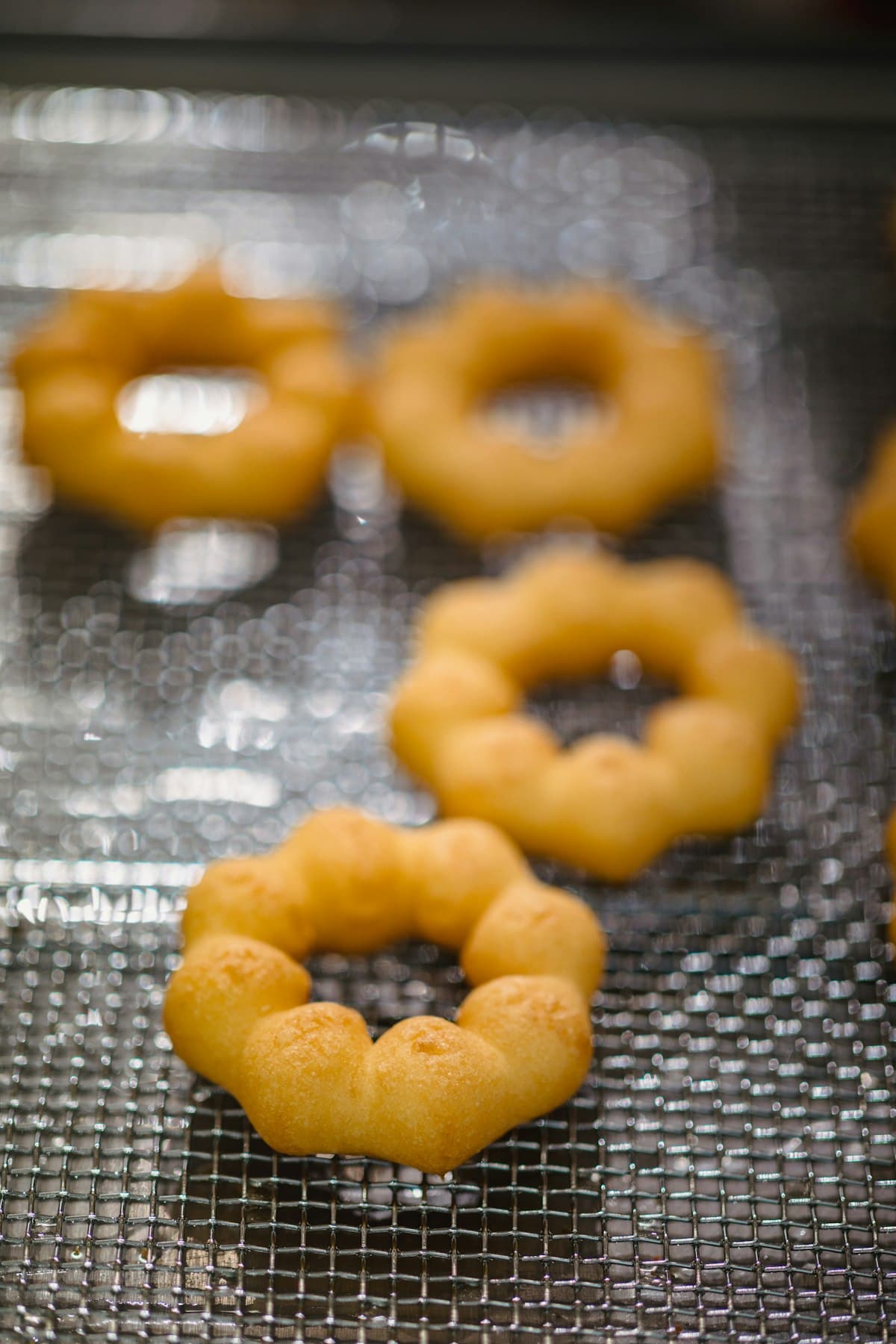 Small flower-shaped fried pastries cooling on a rack