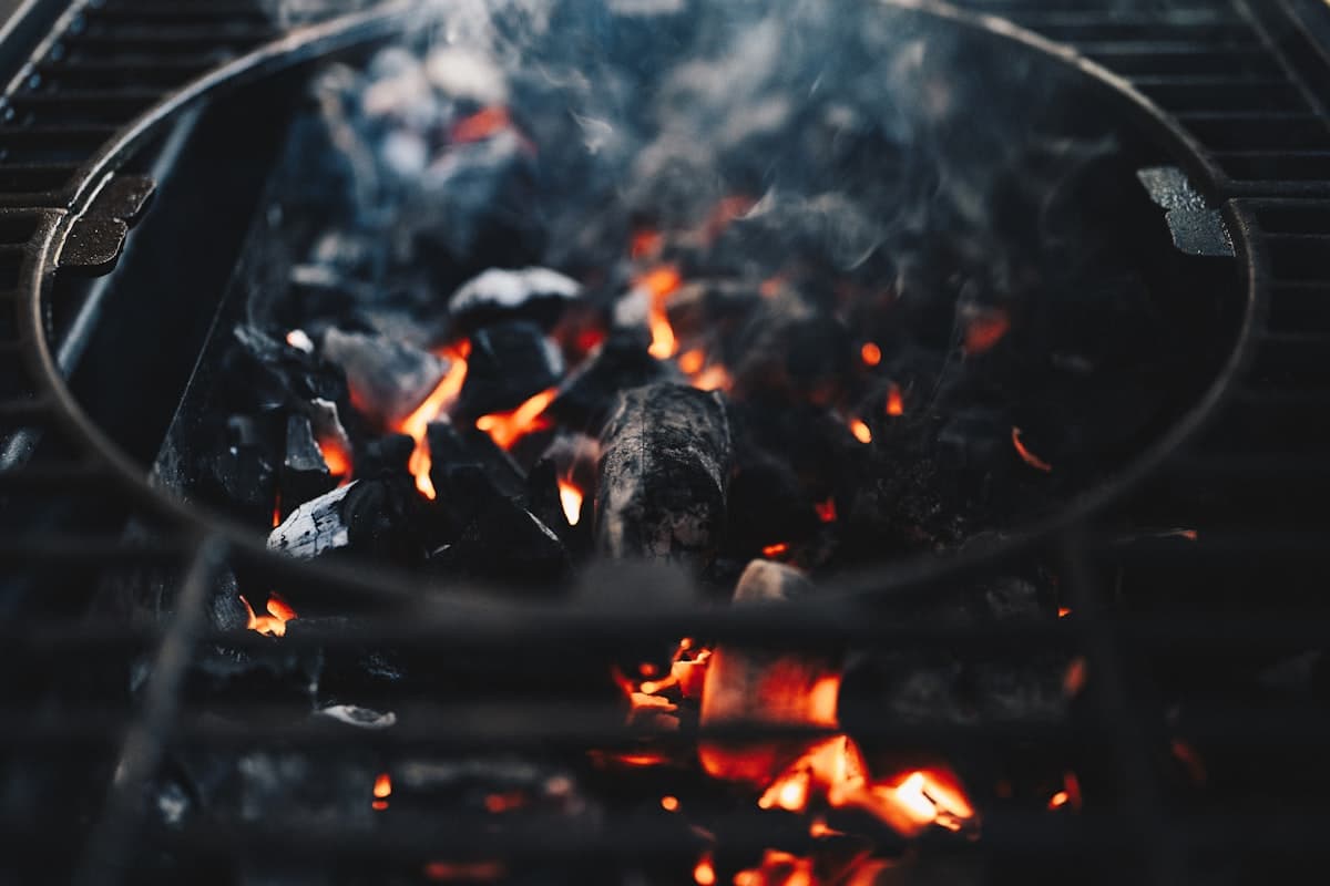 Glowing charcoal embers and flames on a grill