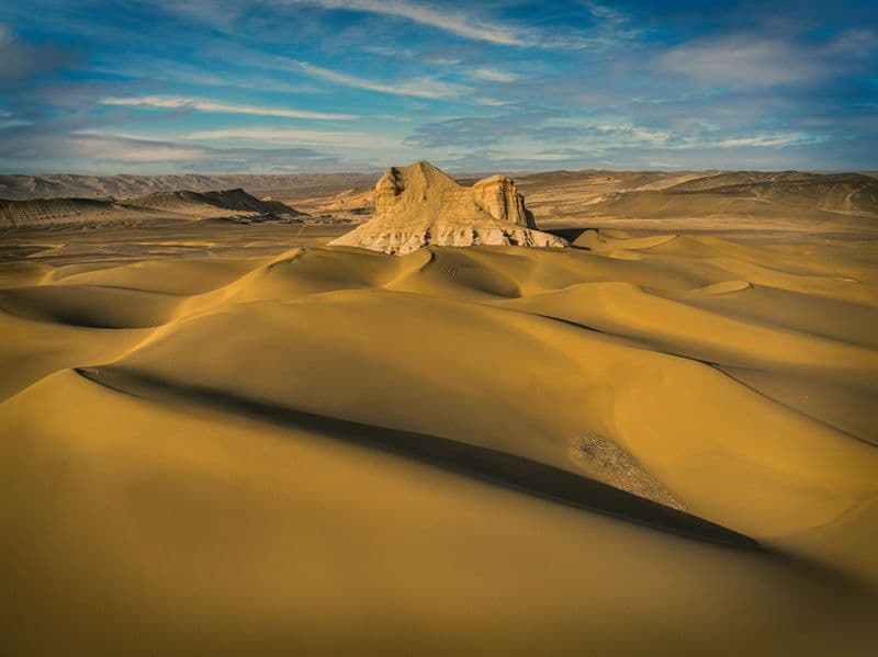 Golden sand dunes stretching toward a rocky outcrop