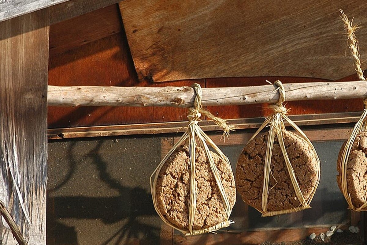 Blocks of fermented soybean meju hung in straw rope under a wooden eave