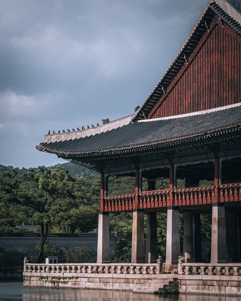 A traditional Korean palace pavilion with tiled roof beside water
