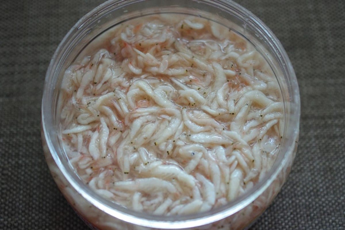 A jar packed with pale, tiny salted fermented shrimp