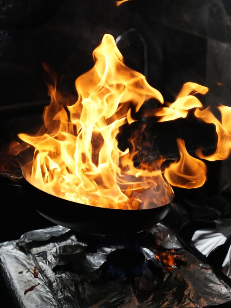 Dramatic flames rising from a wok during high-heat cooking