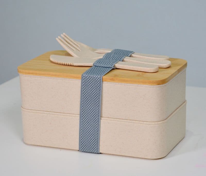 A two-tier wooden lunch box with cutlery on top