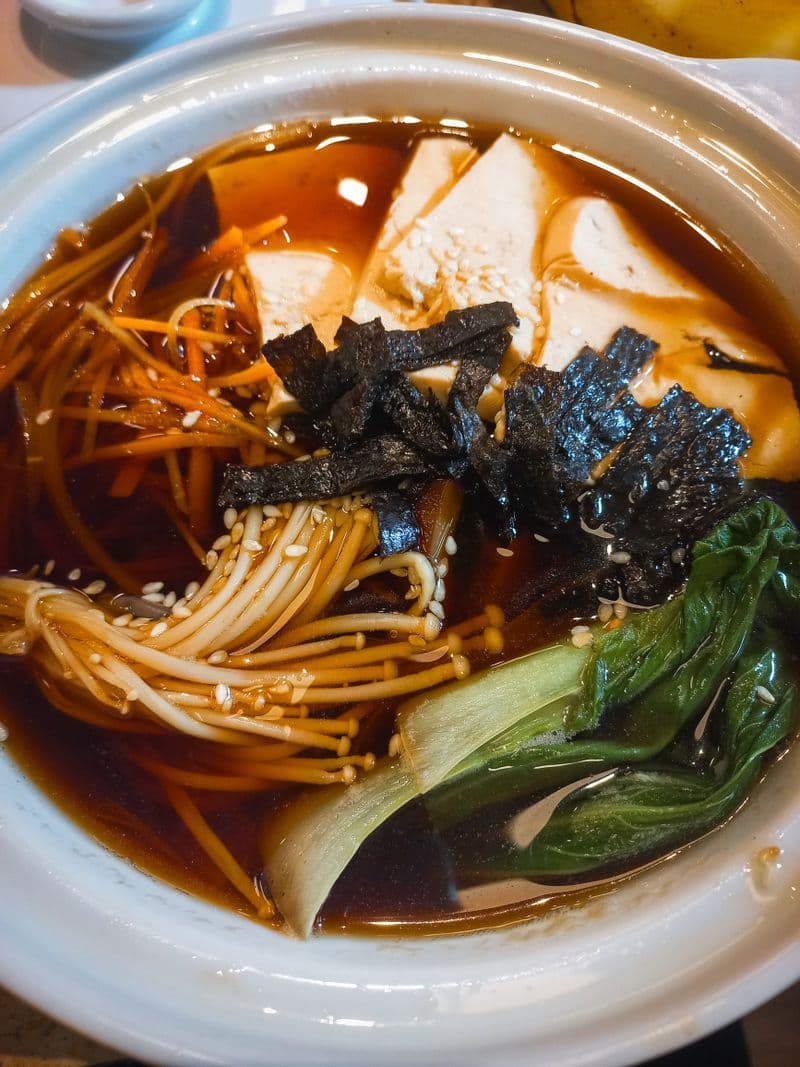 Mushroom hot pot with enoki, tofu, and bok choy in a dark broth