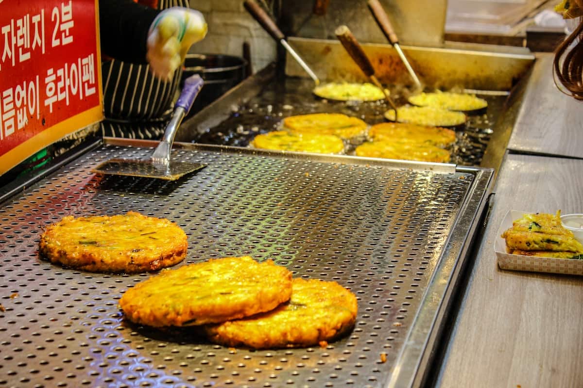 Golden mung bean pancakes frying on a griddle