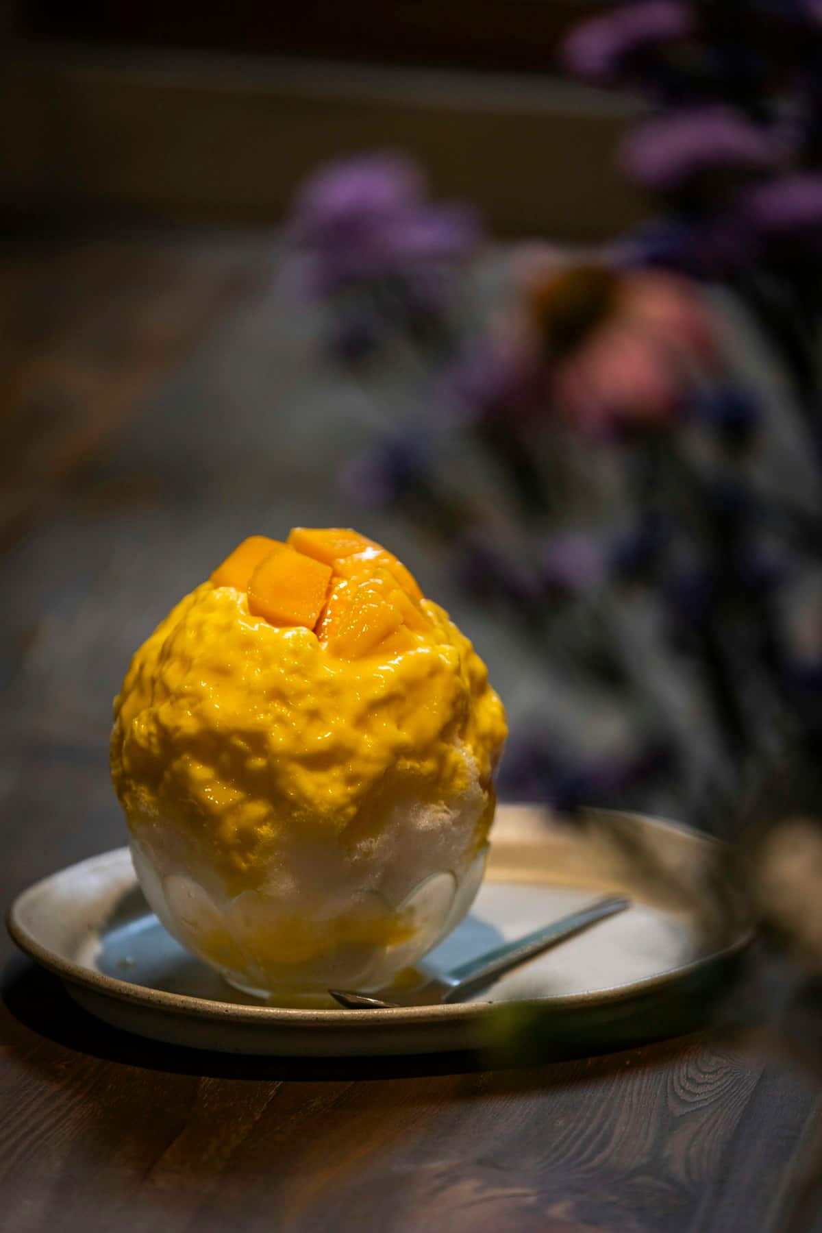 A bowl of shaved ice dessert topped with fruit and condensed milk