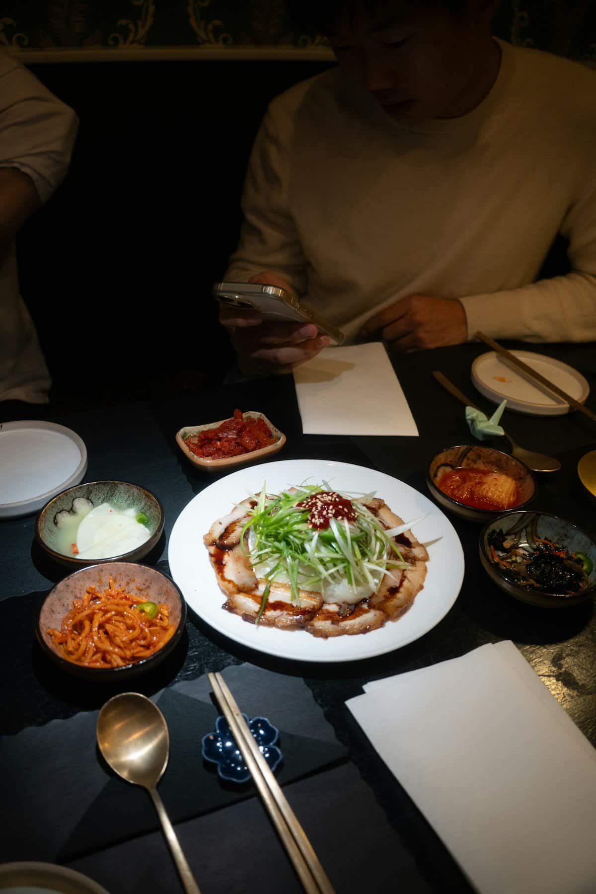 Sliced bossam pork belly on a plate with kimchi and side dishes