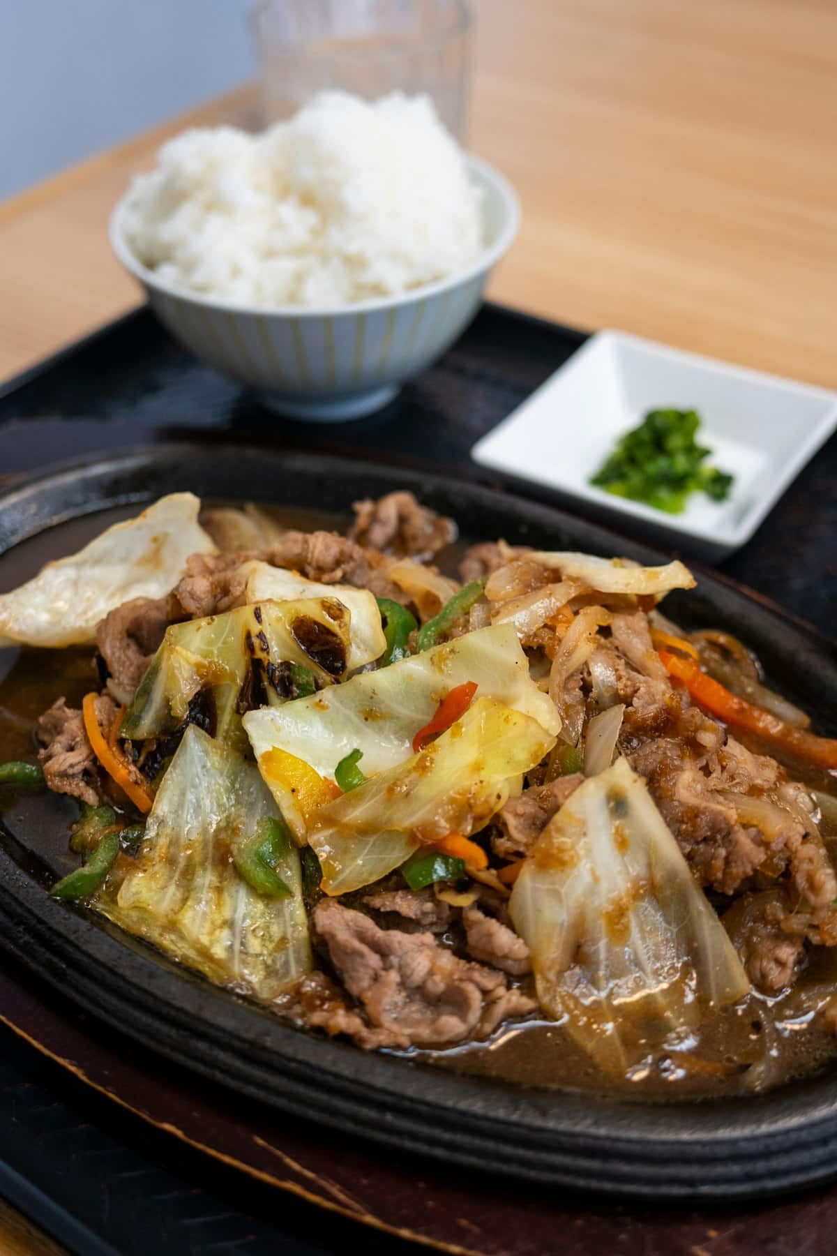 Thin-sliced marinated beef bulgogi with onions on a sizzling plate, served with rice
