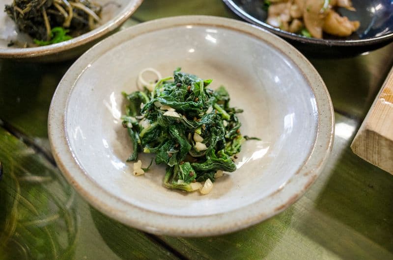 Seasoned dark green namul with garlic in a ceramic bowl