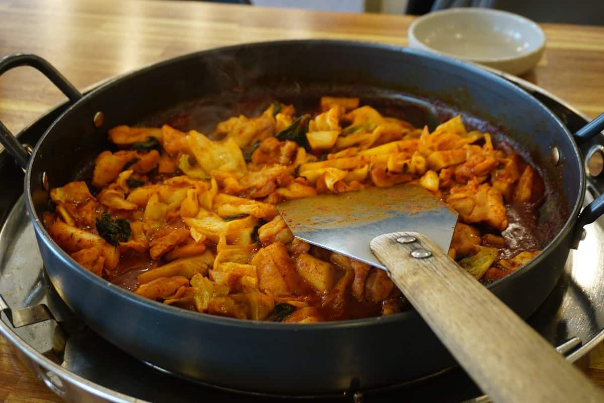 Spicy stir-fried chicken and cabbage in red sauce on a griddle